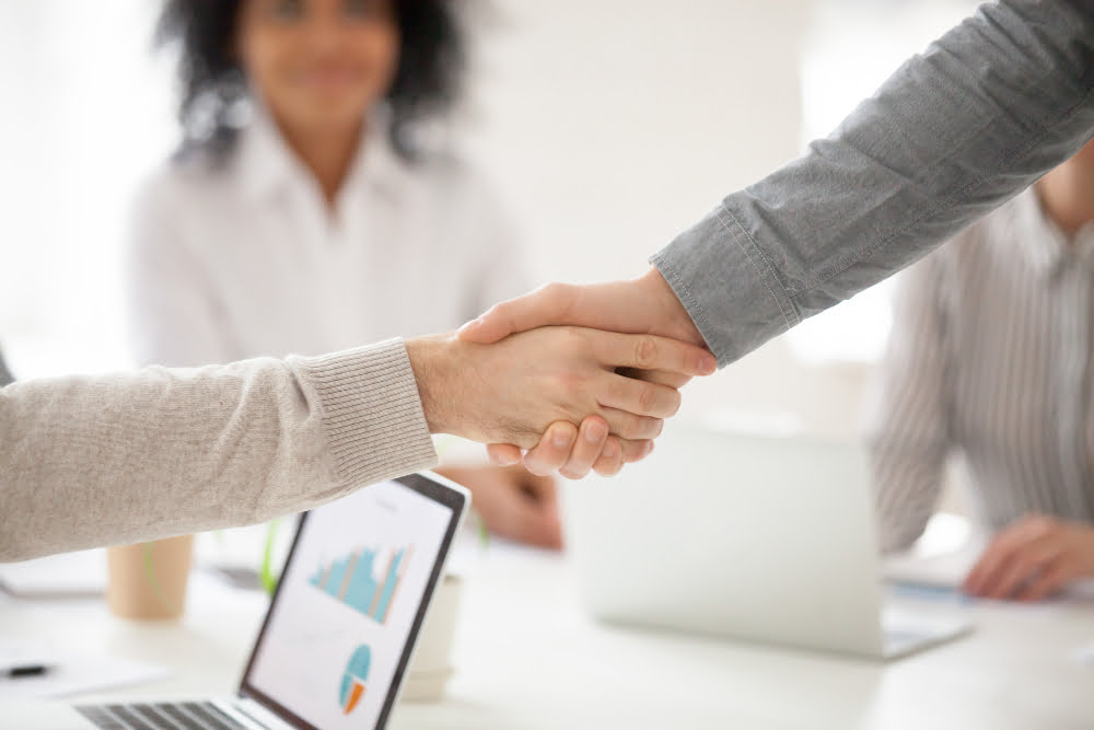 Quais as principais funções do SDR e como se tornar um? 4 business partners handshaking group meeting making project investment closeup