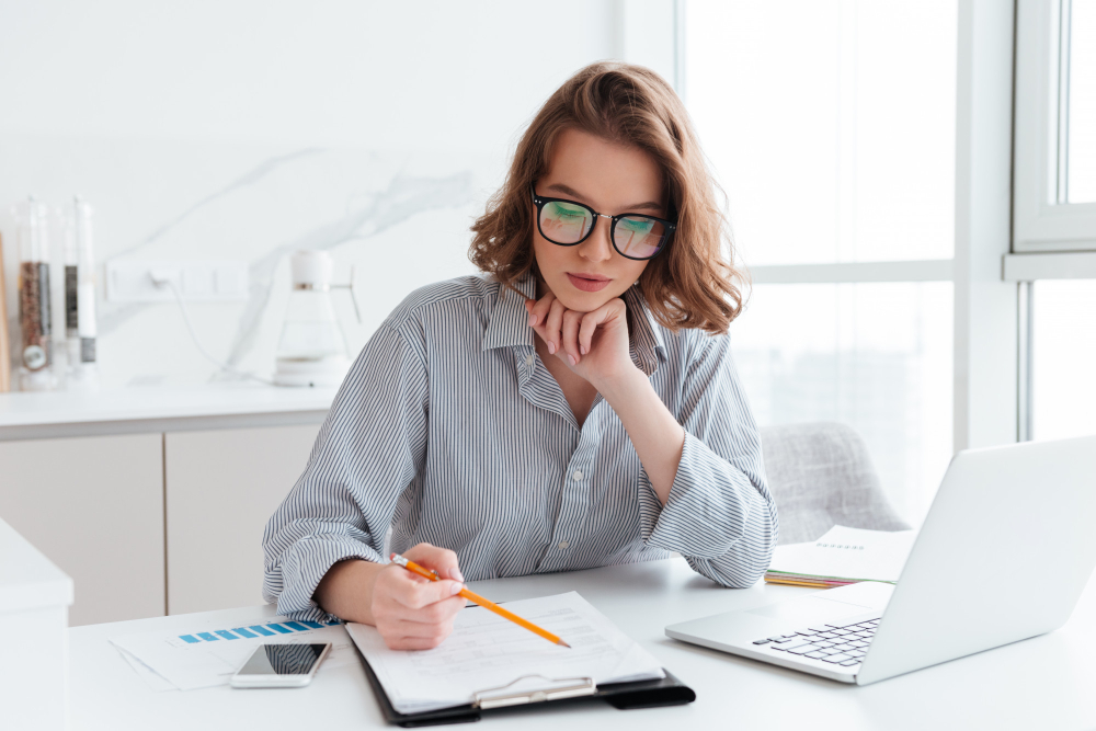 young concentrated businesswoman glasses striped shirt working with papers home