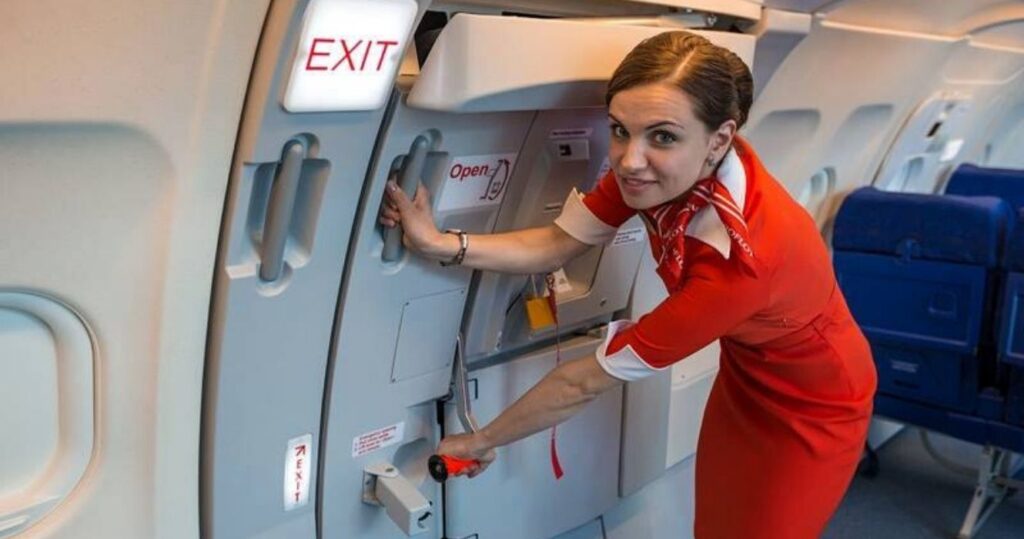 15 coisas que os comissários de bordo fazem ao lidar com passageiros irritantes 15 Flight attendant at the exit door of an airplane