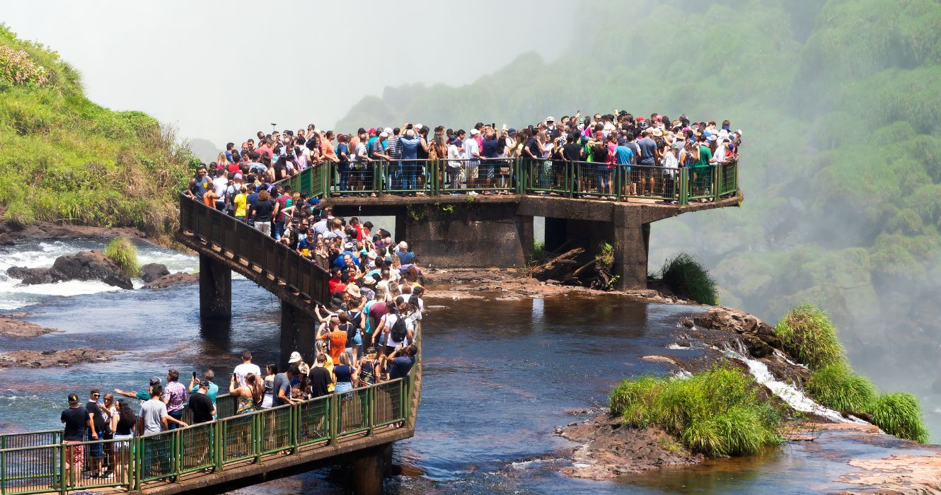 O que é excesso de turismo e o que podemos fazer para impedi-lo? 1 turistas lotados na ponte do iguasso no brasil, overtourism