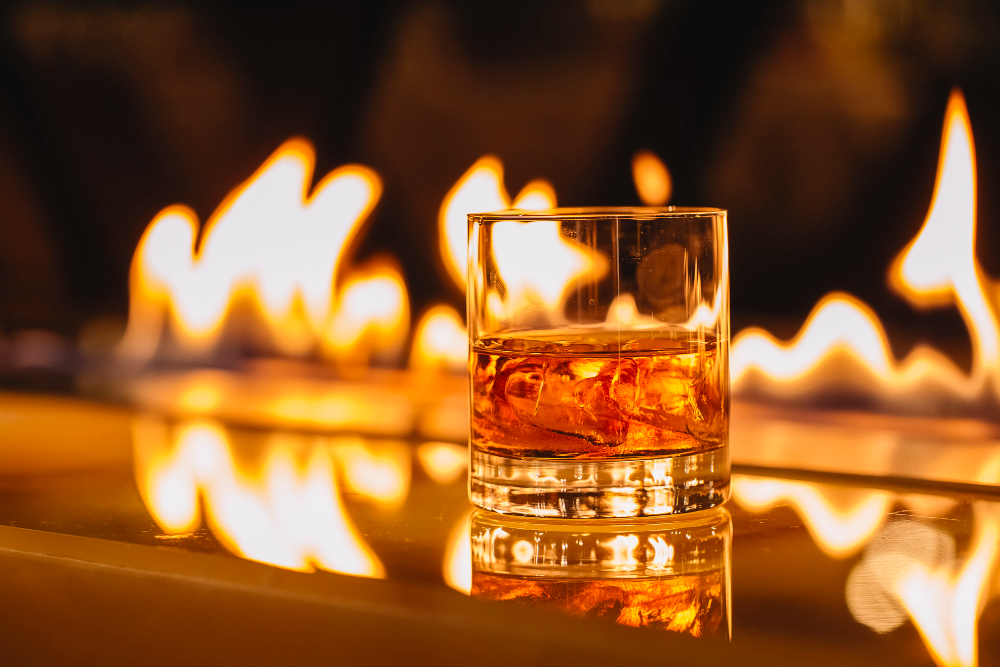 side view glass whiskey with ice background burning flame