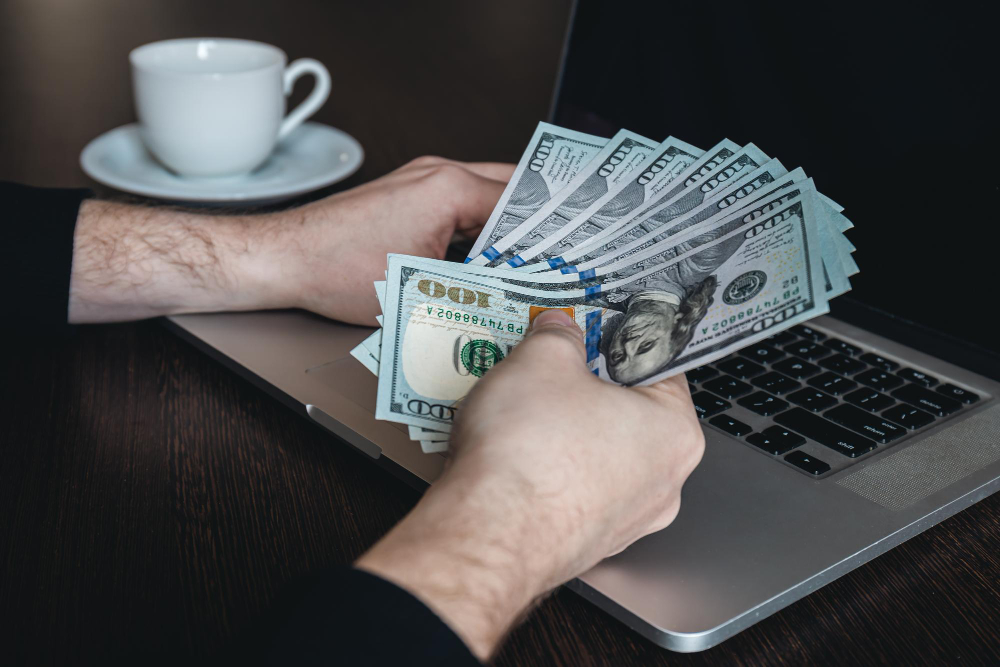 Como ganhar em dólar em casa? 3 notas de dolar fechadas em maos masculinas o conceito de ganhar dinheiro e trabalhar